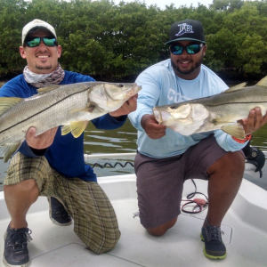 Two guys holding fish on boat