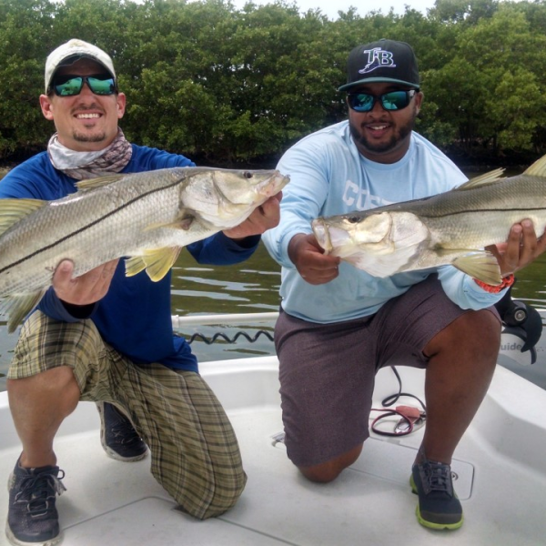 Two guys holding fish on boat
