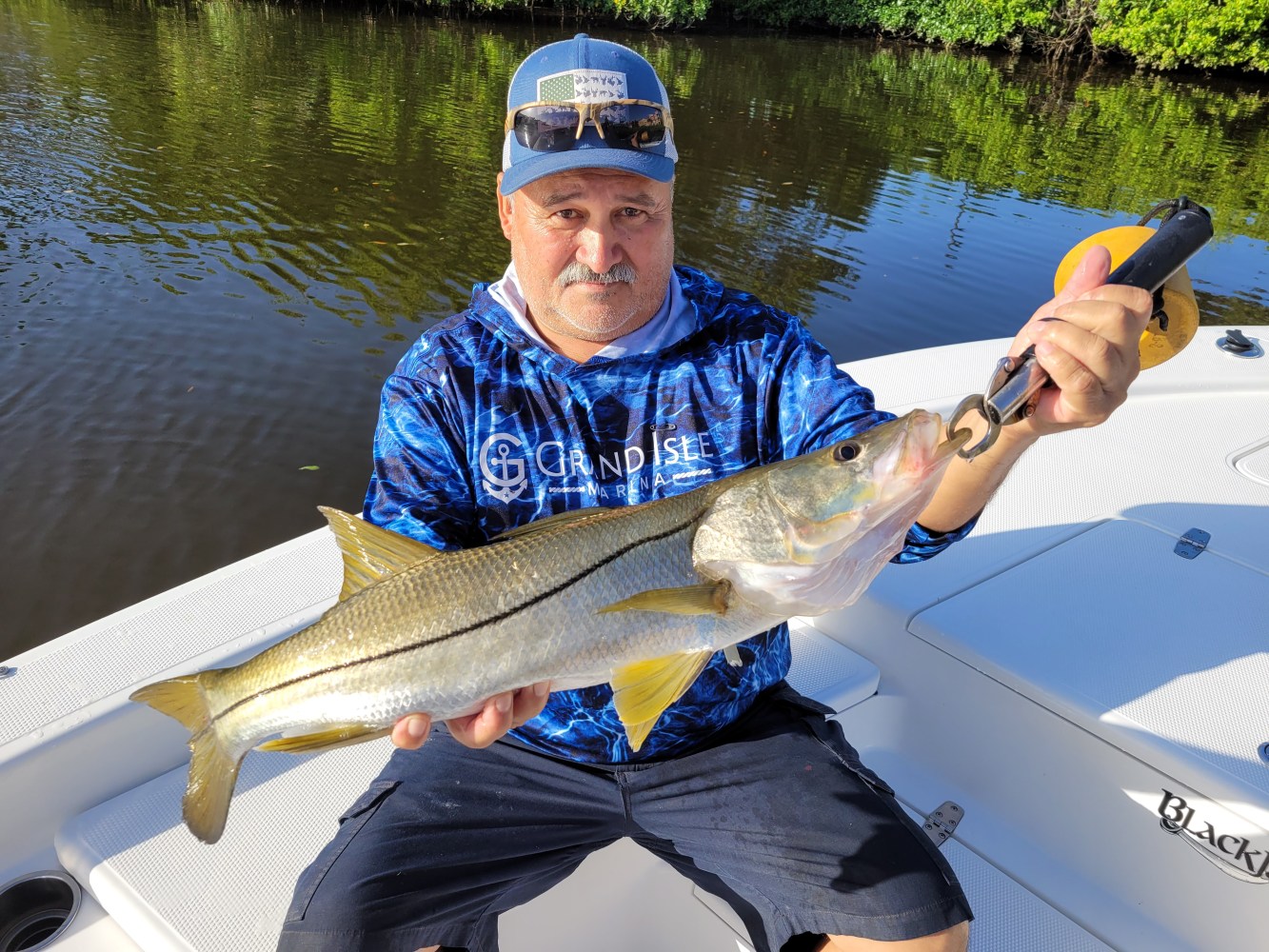 a man holding a fish on a boat in a body of water