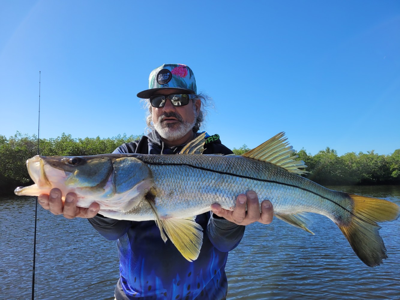 a man holding a Snook in the water