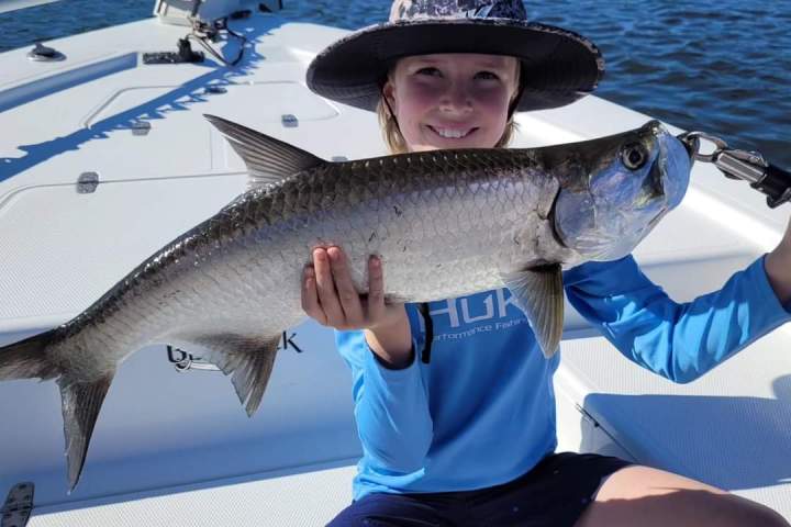 a woman holding a fish on a boat in the water