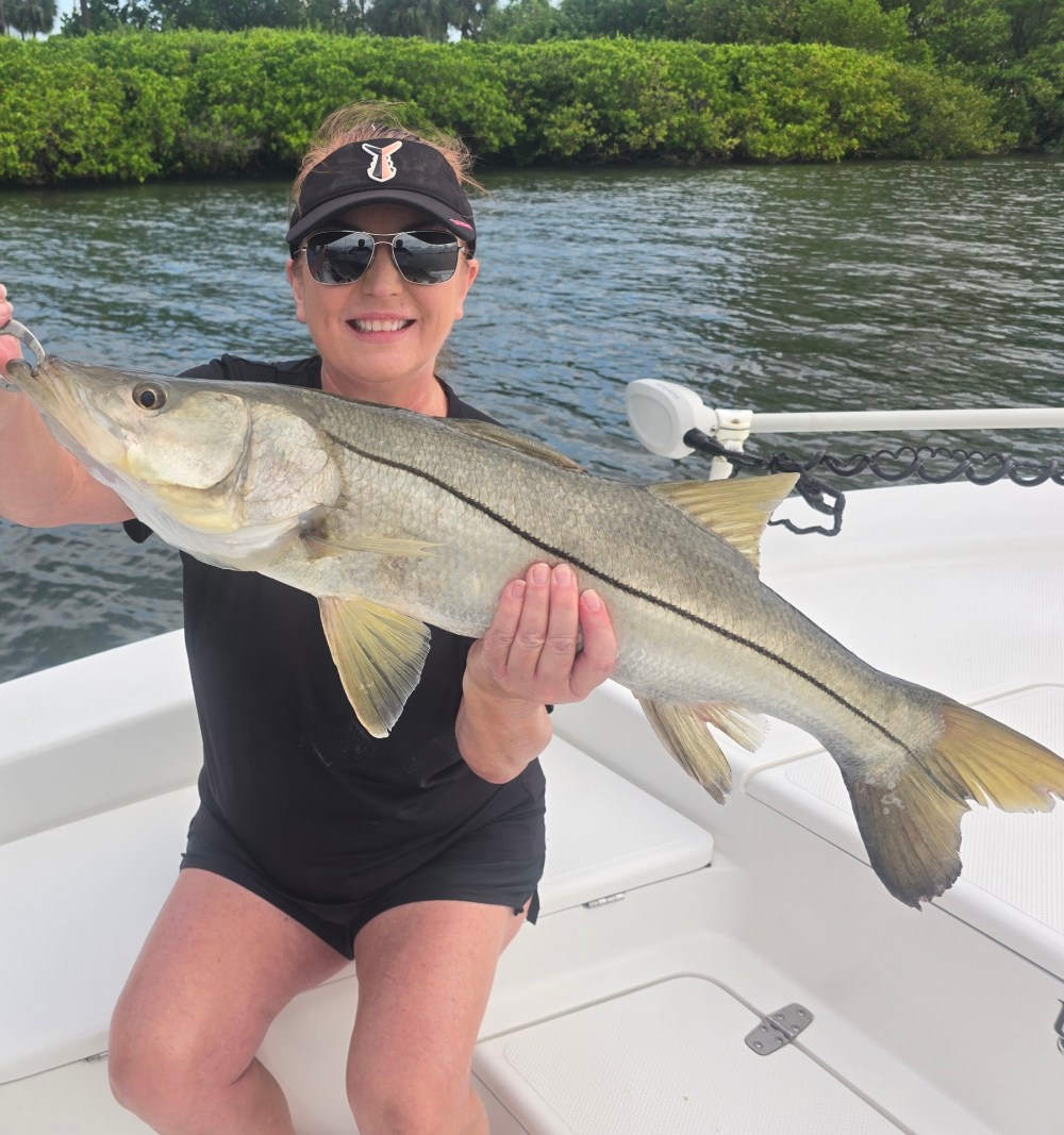 Person holding a large fish on a boat near water.